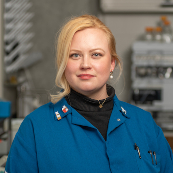 Smiling woman with blonde hair, in blue lab coat.